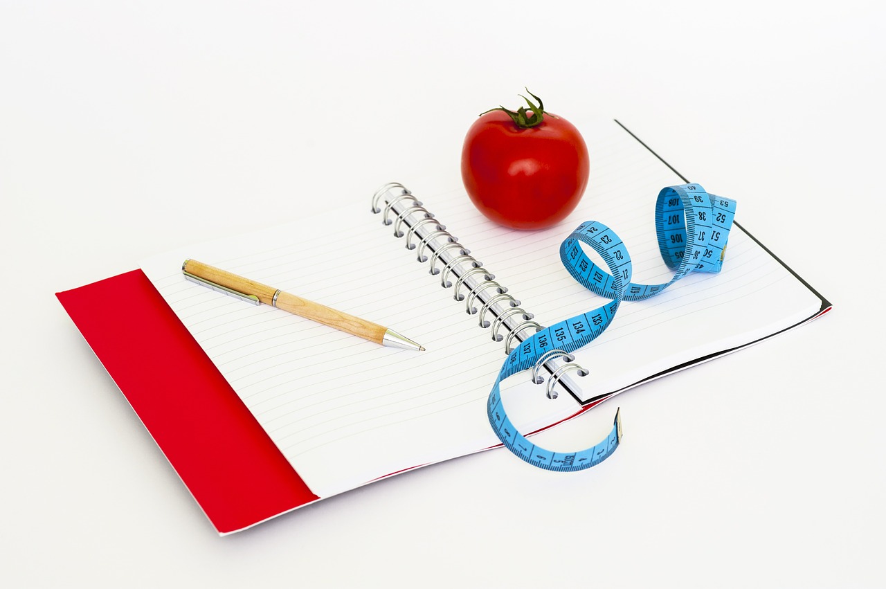 Notebook, tomato and measuring tape